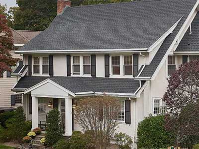 Front view of a white mid-class home with dark gray GAF shingles on its roof