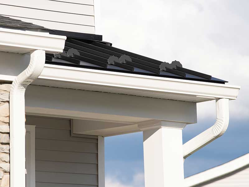 Two white, k-style gutters with downspouts, both attached to the fascia of a home