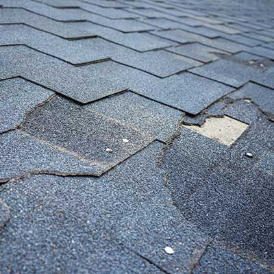 Close up of shingles that are broken and ripped apart due to a storm